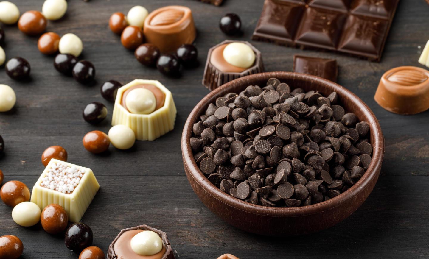 choco-drops-with-chocoballs-choco-bars-caramel-clay-bowl-wooden-table.jpg